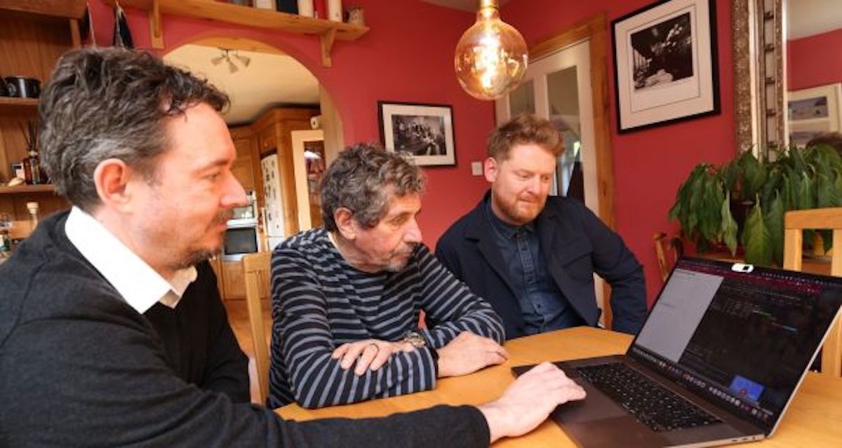 Keith, Charlie and Trevor gather around a laptop.