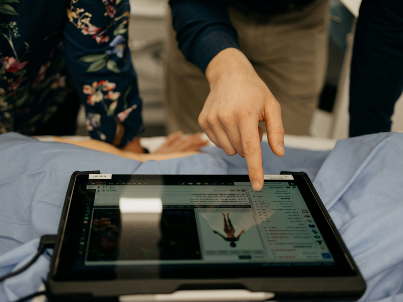 A hand pointing at a medical app on a tablet