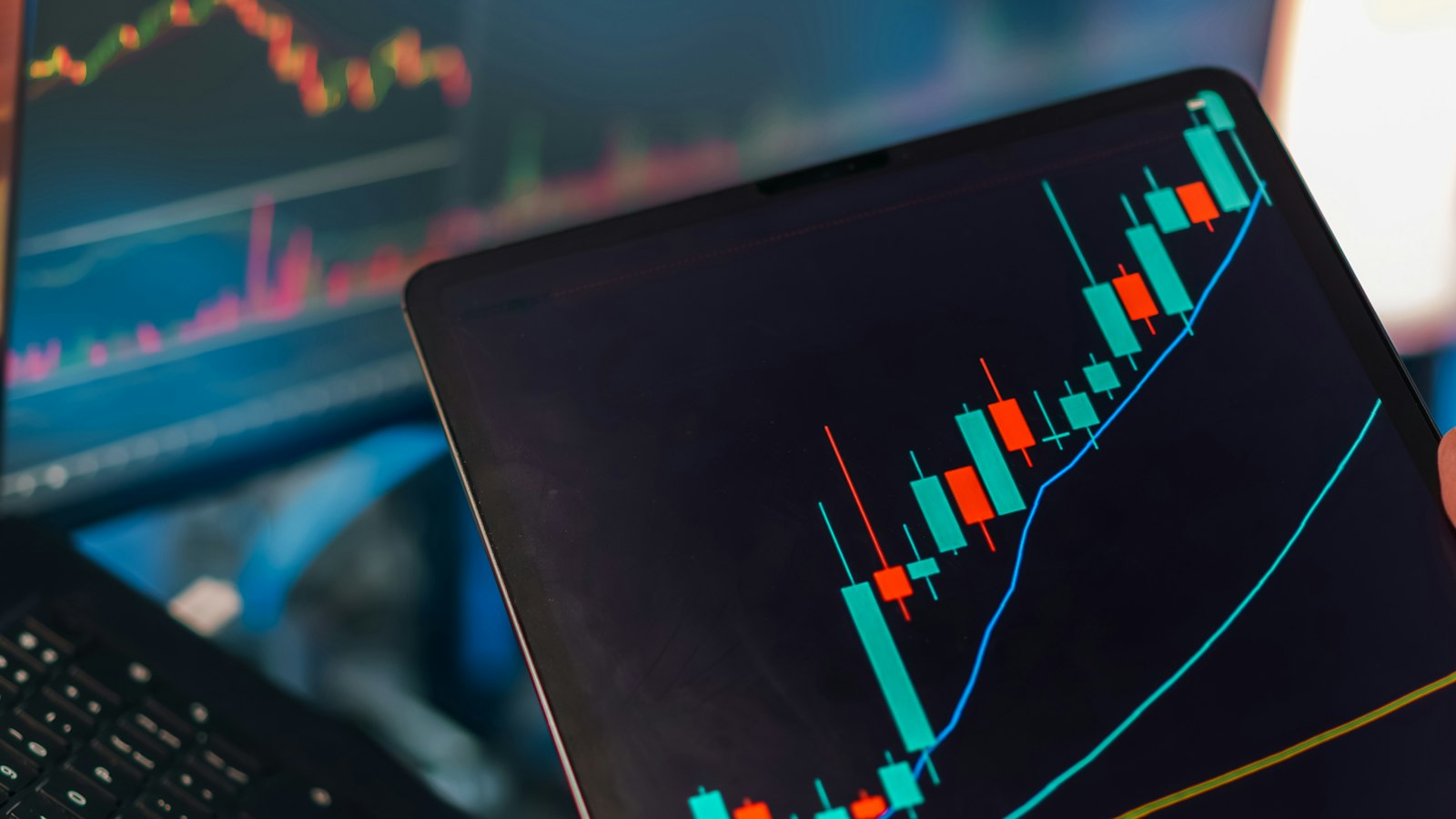 Tablette affichant un graphique boursier ascendant devant des écrans de trading
