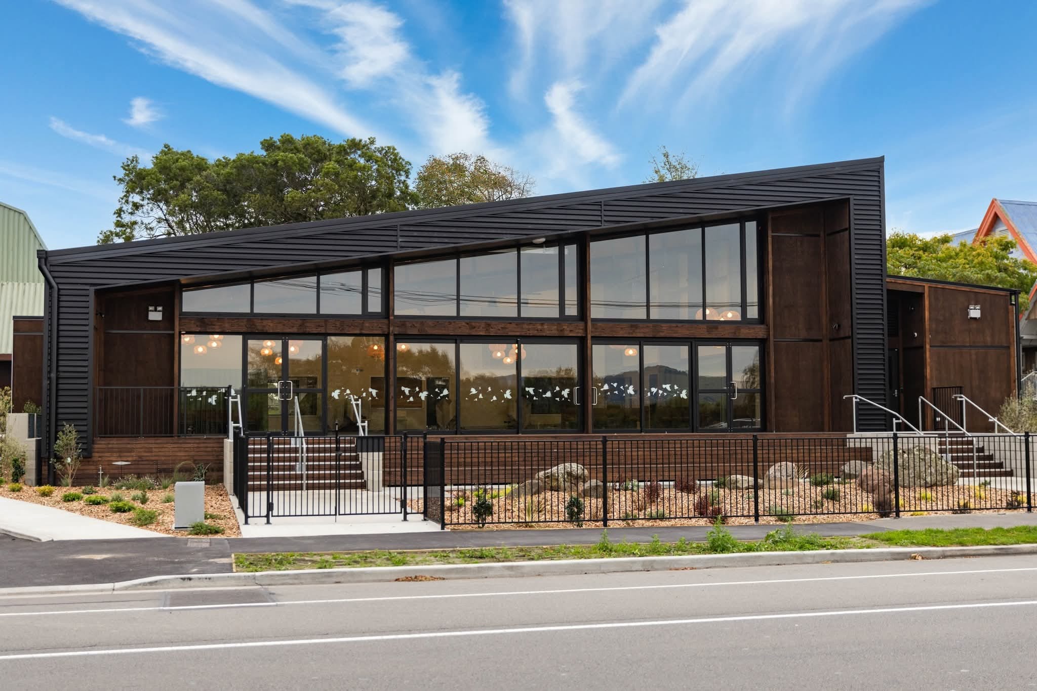 The front of a modern church building. Black angular frame and glazed frontage.