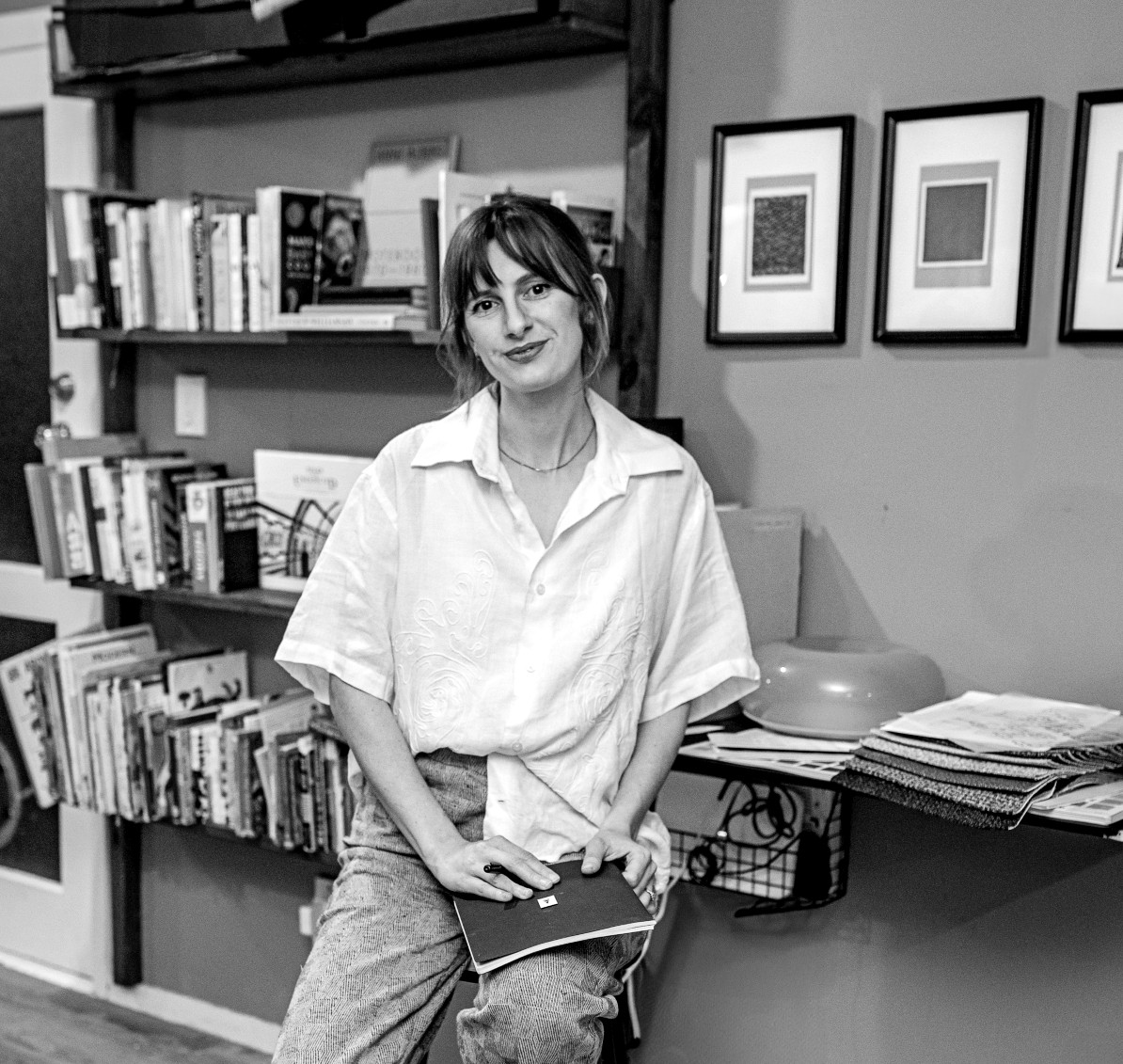 A black and white image of a woman holding a notebook.