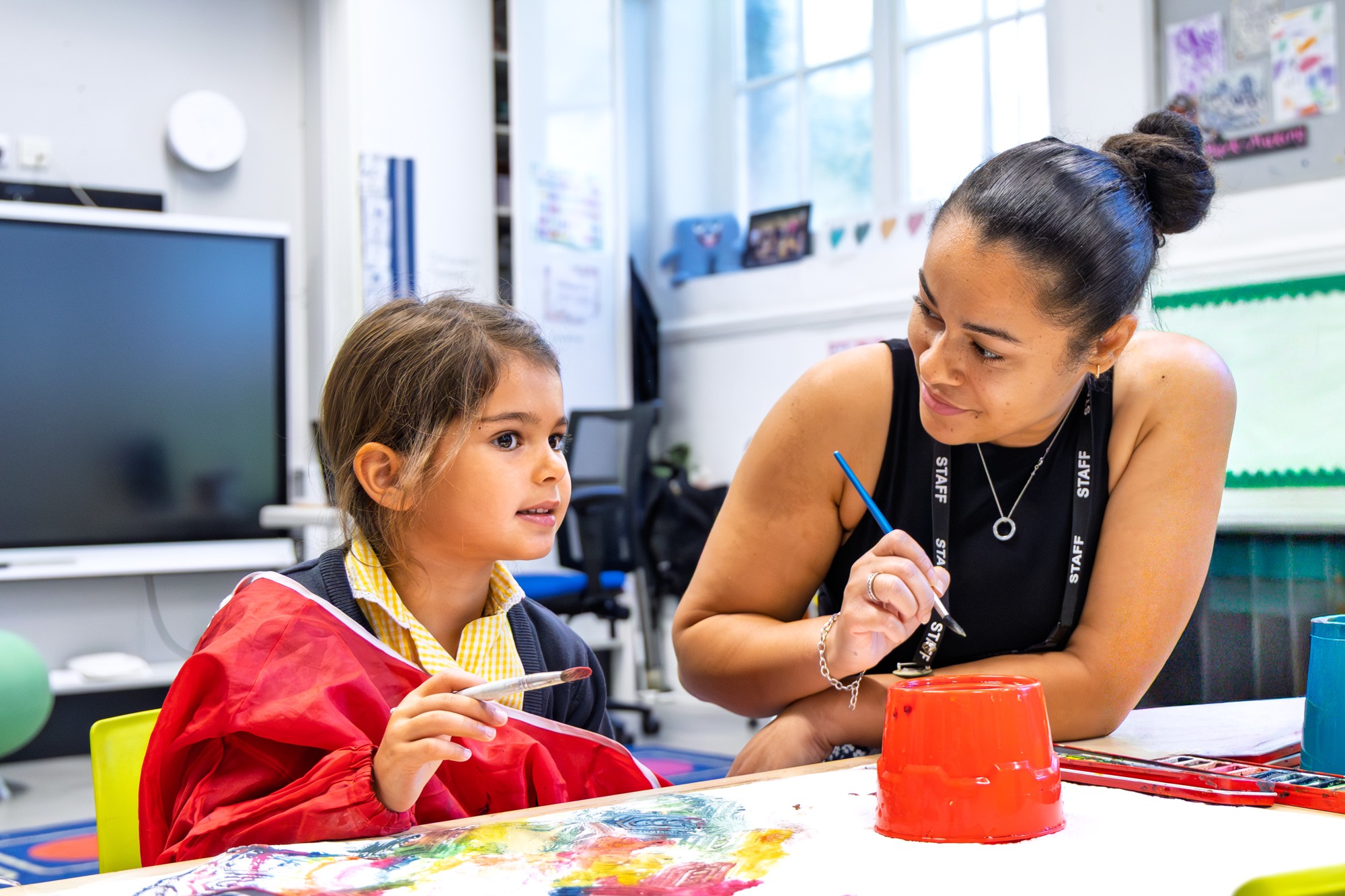A teacher teaching art to a reception aged student