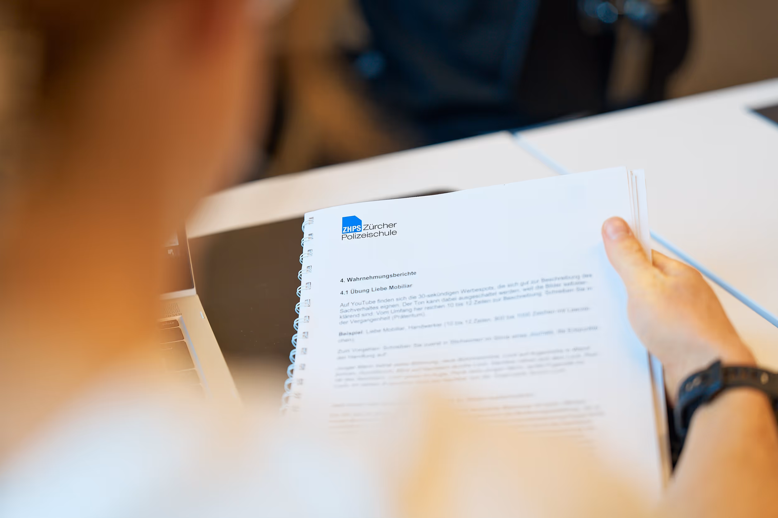 Person liest ein spiralgebundenes Dokument der Zürcher Polizeischule