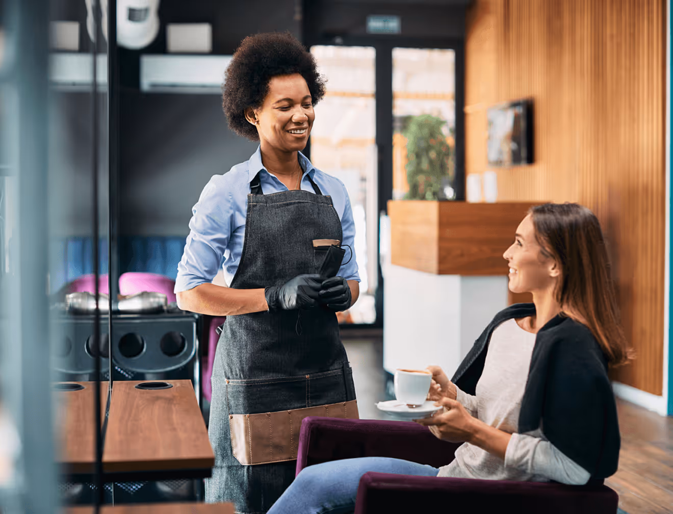 Friseurin berät lächelnd eine Kundin im Salon.