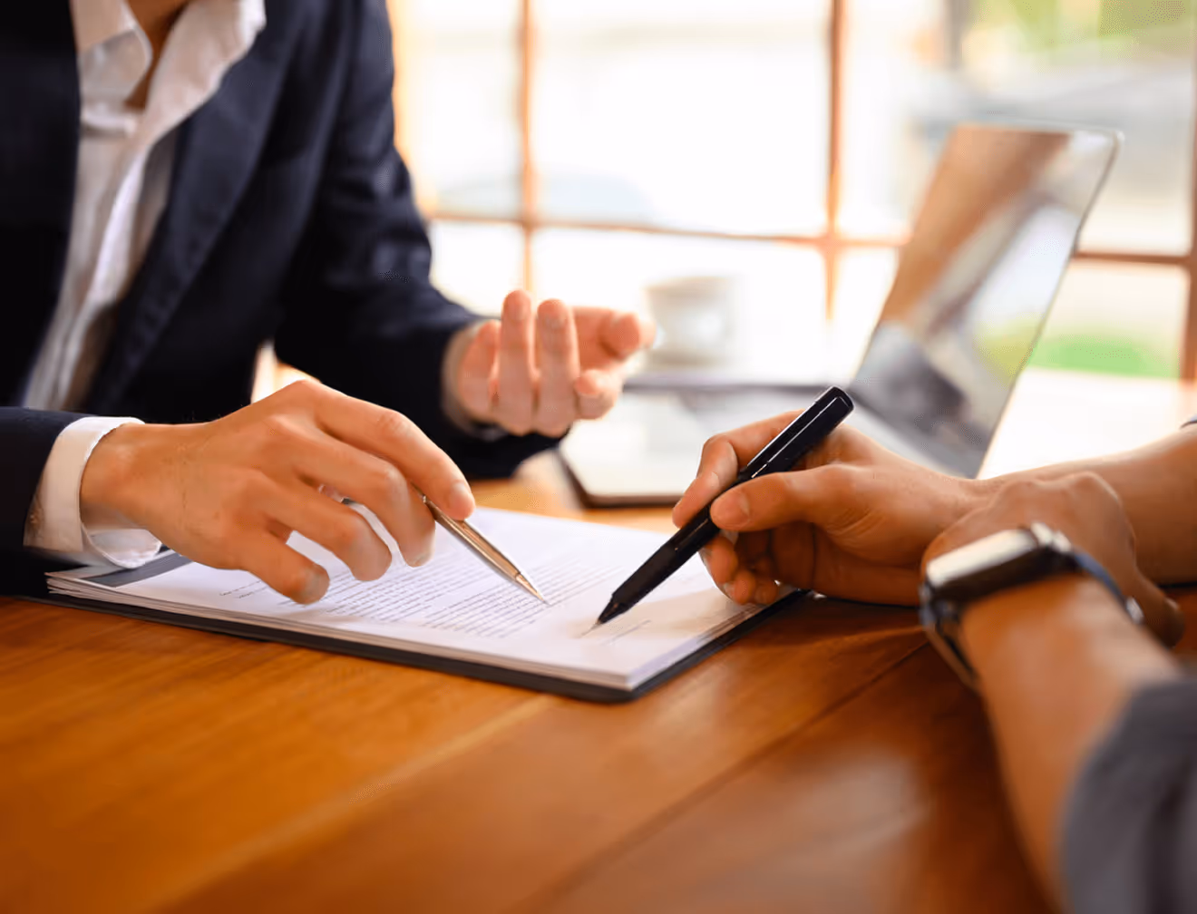 Vertrag wird auf einem Tisch unterschrieben, Hände mit Stift und Tablet sichtbar.