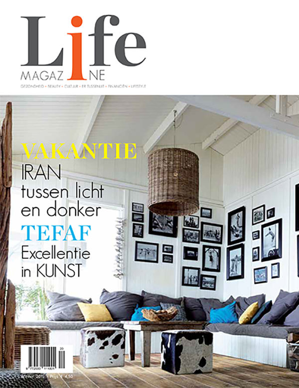 Cozy living room with gray sectional sofa, colorful cushions, cowhide ottomans, rustic wooden coffee table, and a gallery of black-and-white photos on white paneled walls under a wicker pendant light.