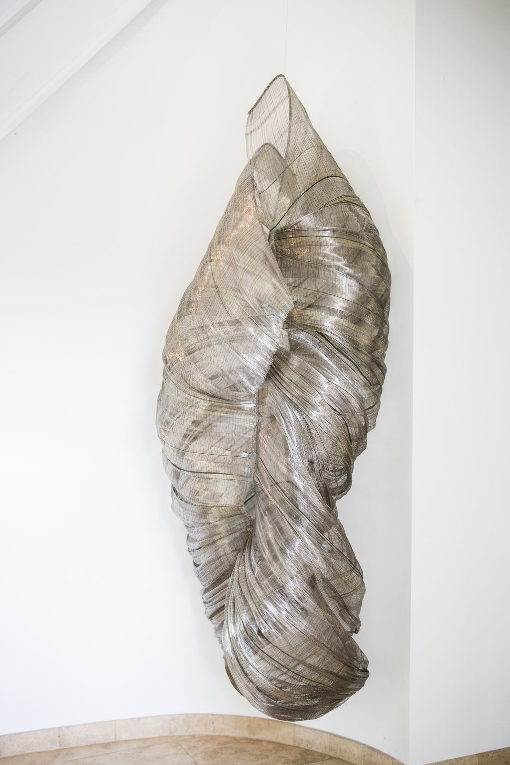 The Cocoon Floating Sculpture by Belgian artist Adeline Halot is a delicate, suspended artwork crafted from fine wire. It evokes a sense of lightness and transformation, resembling an organic cocoon mid-metamorphosis—hovering between fragility and st
