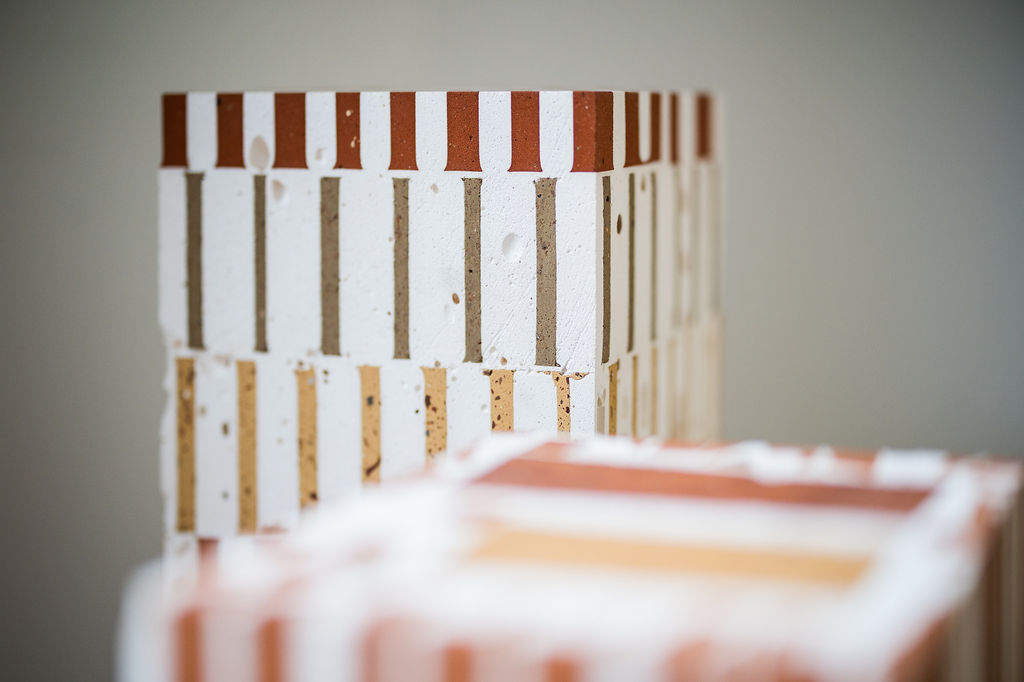 Side perspective of Aurélien Veyrat’s [aglɔmeʀa] sculpture, revealing its architectural structure, rhythmic patterns, and earthy tones.Close-up of [aglɔmeʀa] by Aurélien Veyrat, highlighting the raw materiality, porous surfaces, and intricate geometric composition.