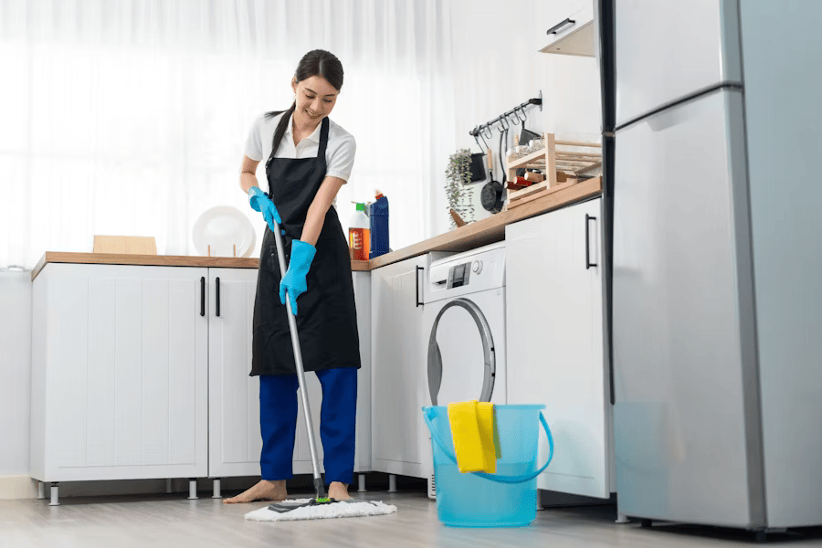 Eine Mitarbeiterin von Karma Service reinigt sorgfältig den Boden in einer modernen Privatküche in Düsseldorf im Rahmen einer professionellen Haushaltsreinigung.