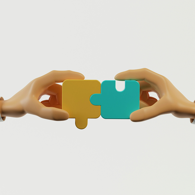Two hands each holding a puzzle piece, fitting a yellow and blue piece together against a plain background.