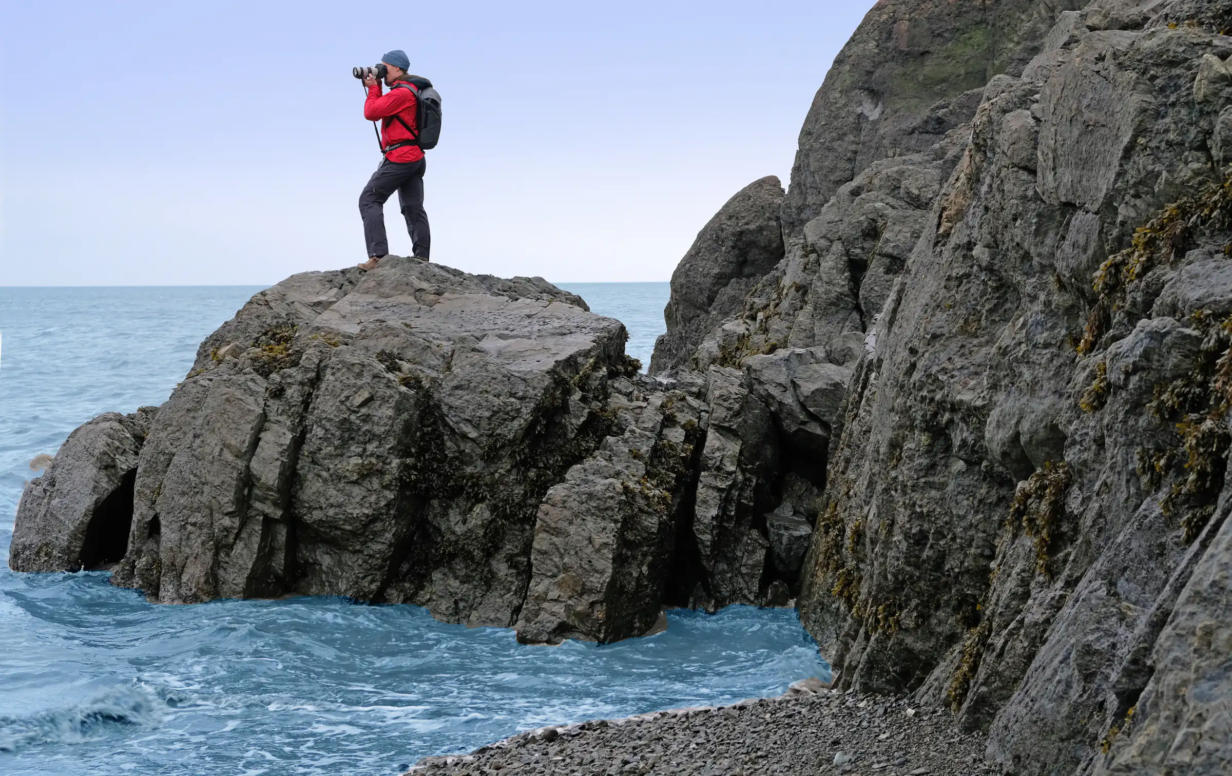 Photographer in a red jacket using a Steadify on a rock outcrop above the sea at Beluga Point