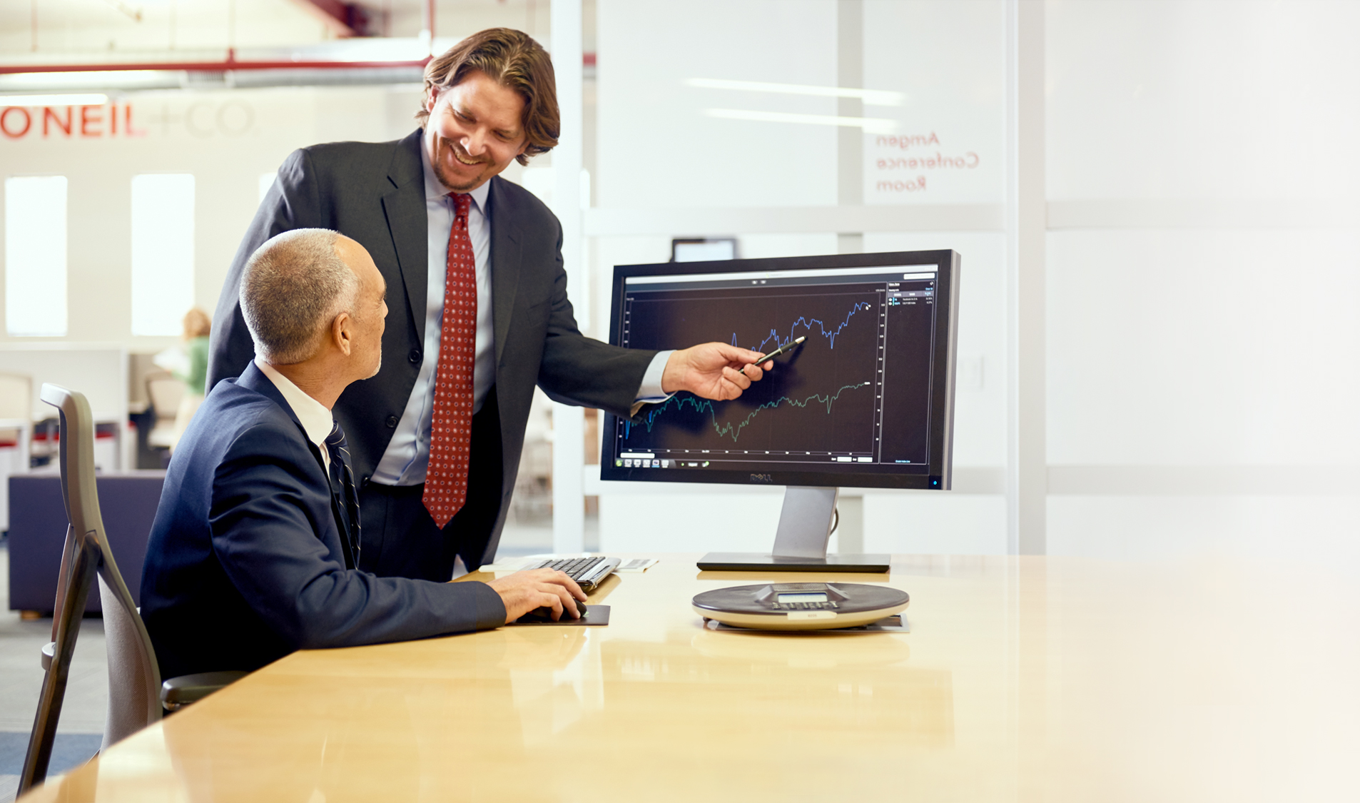 Two William O'Neil analysis going over charts on a desktop computer.