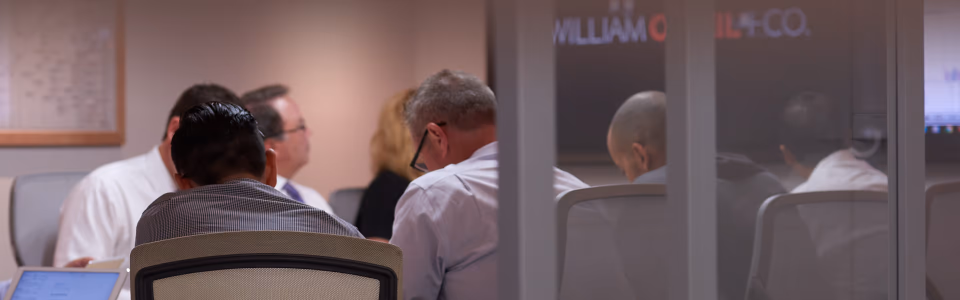 A group of William O'Neil employees having a meeting in a conference room.