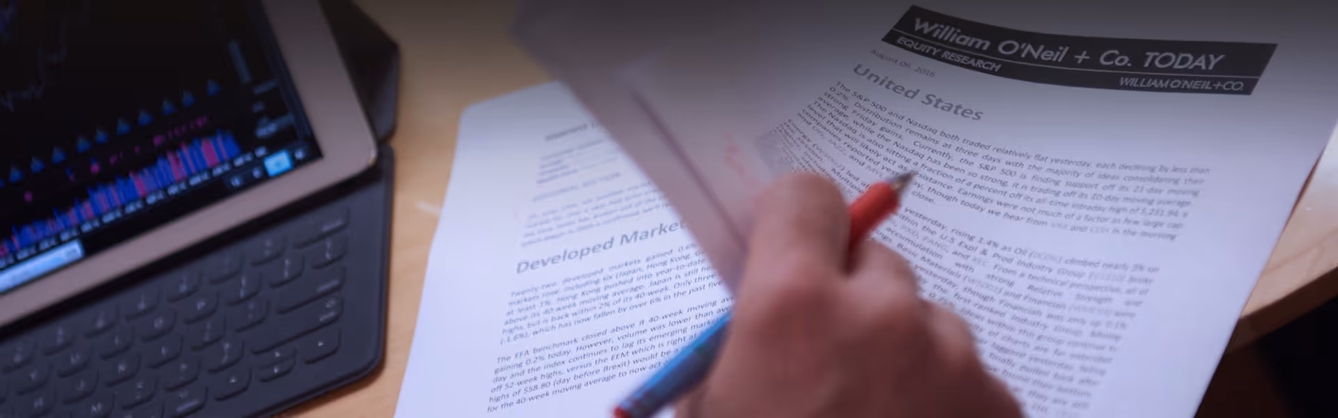 A close up image of a hand turning papers on a desk.