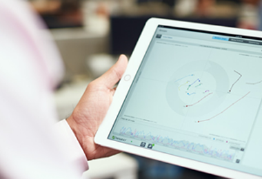 someone holding an iPad with a stock chart displayed on the screen.