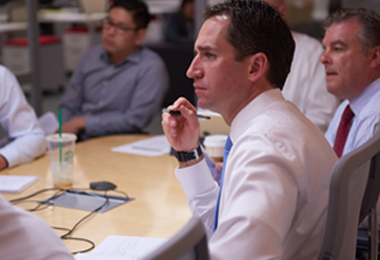 An image of the William O'Neil team in a meeting discussing their research products.