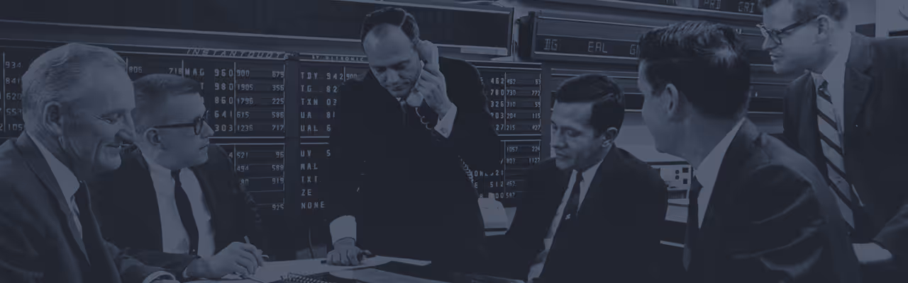 An image of a young William O'Neil in a meeting with his team.