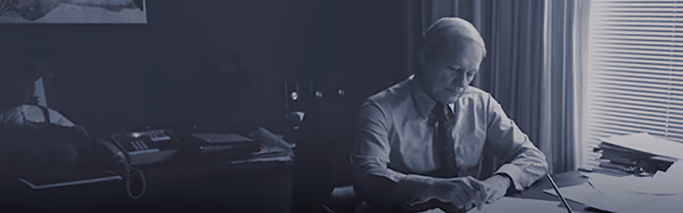 An image of William J. O'Neil sitting at his desk reviewing papers.