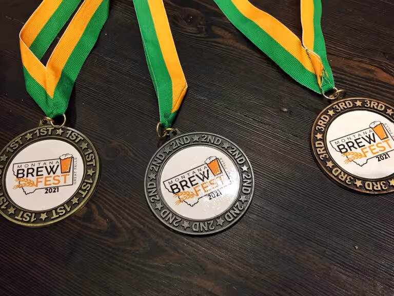 Three medals with green and yellow ribbons on a dark wood surface.