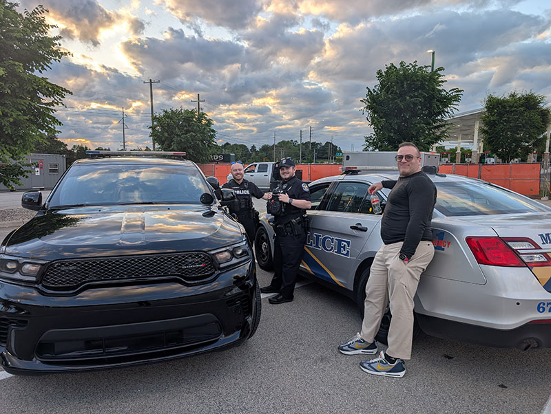A photo of Kiril with the IMPD standing by their police vehicles.