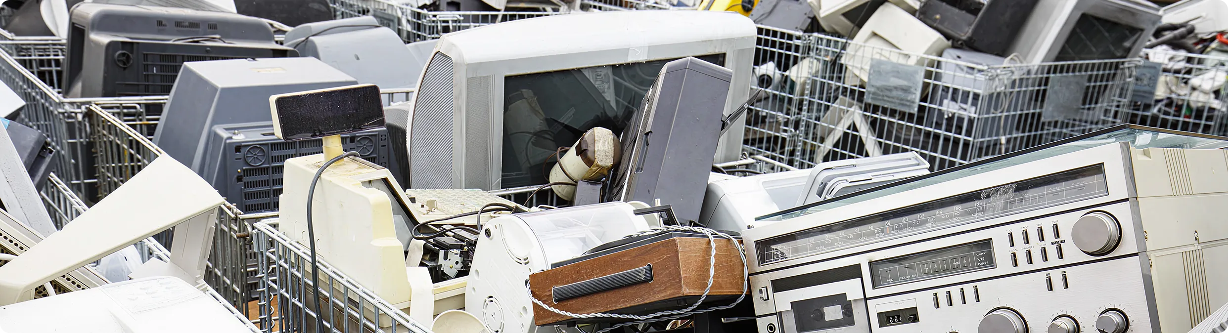 Discarded old electronics including monitors, radios, and keyboards.