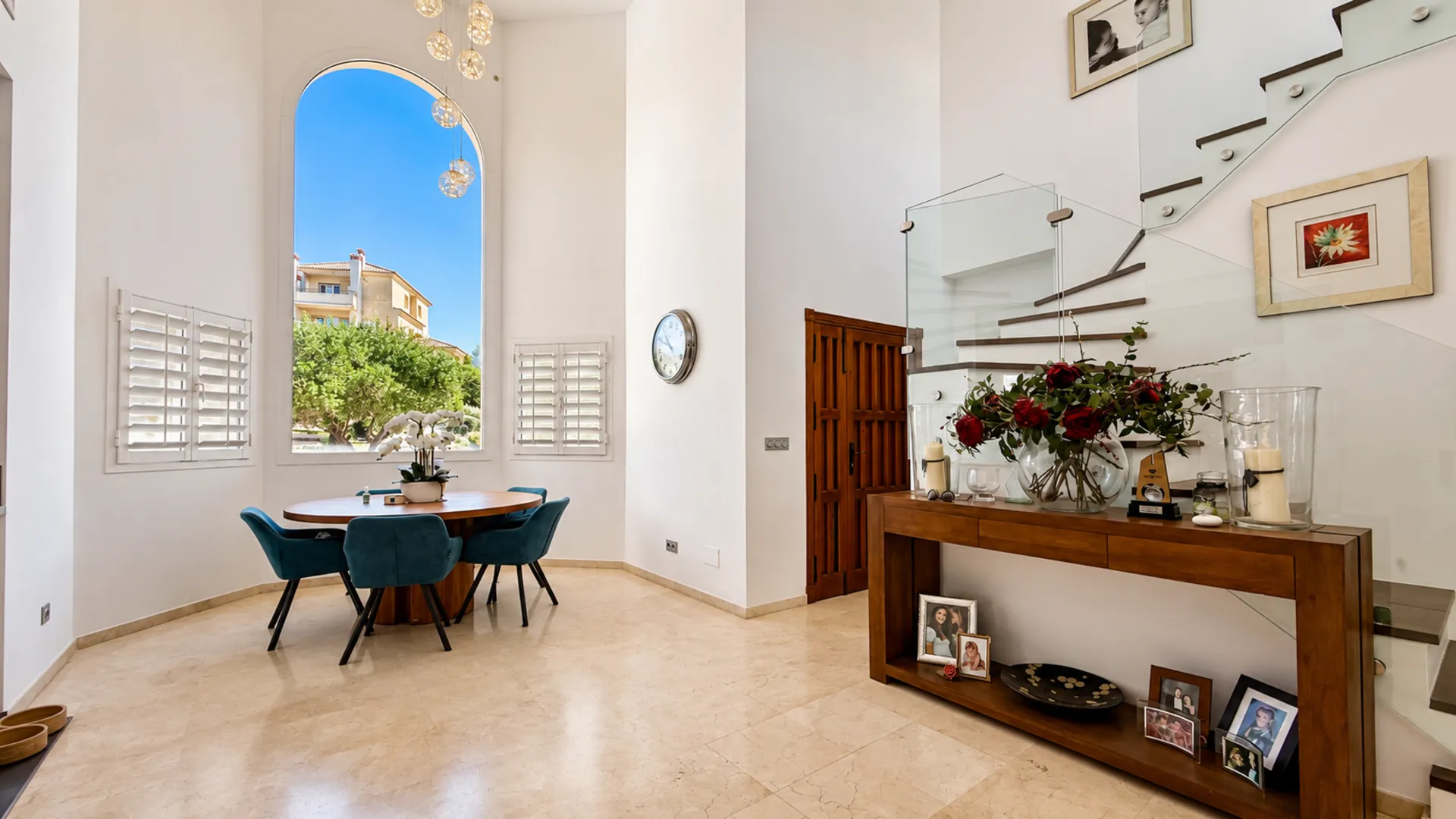 Double-height entrance hall of the San Roque Club penthouse with dining table, floating staircase and arched window
