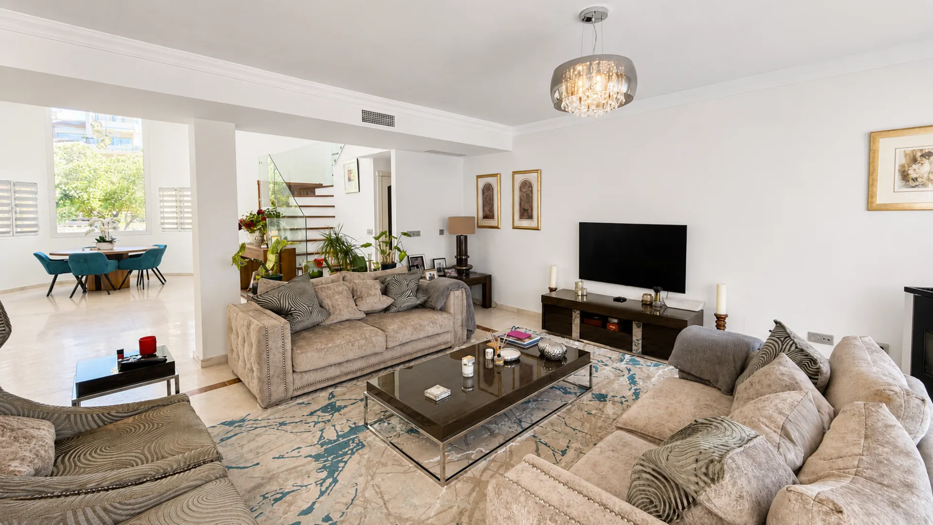 Bright open-plan living room in the San Roque Club penthouse with sectional sofas, coffee table, TV and view through to dining area