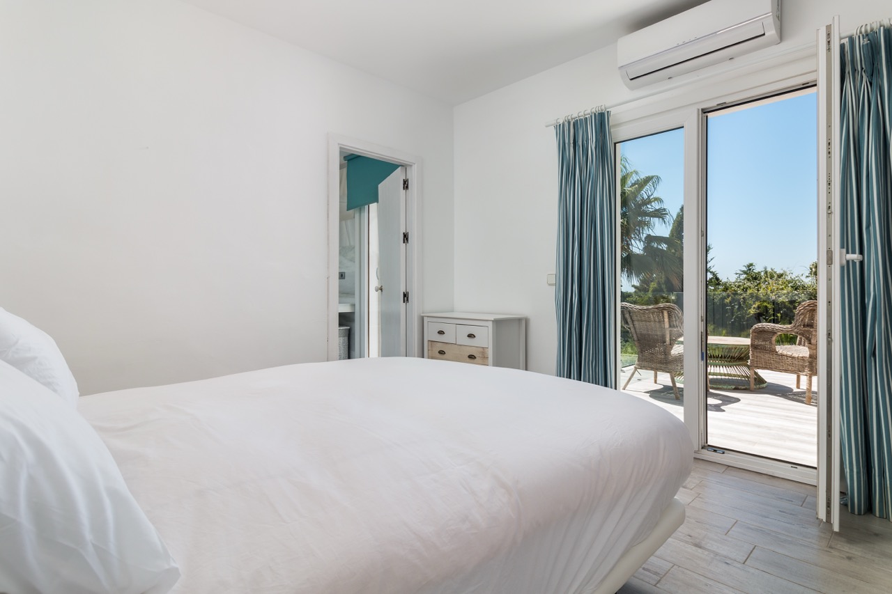 Dormitorio con puertas a la terraza, luz natural y vistas al jardín
