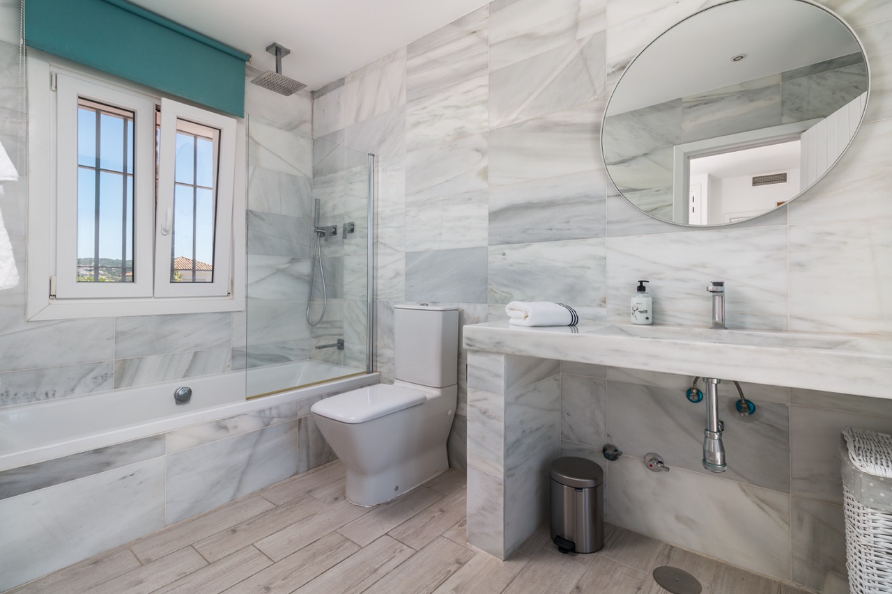 Baño con doble lavabo, bañera y acabados efecto mármol