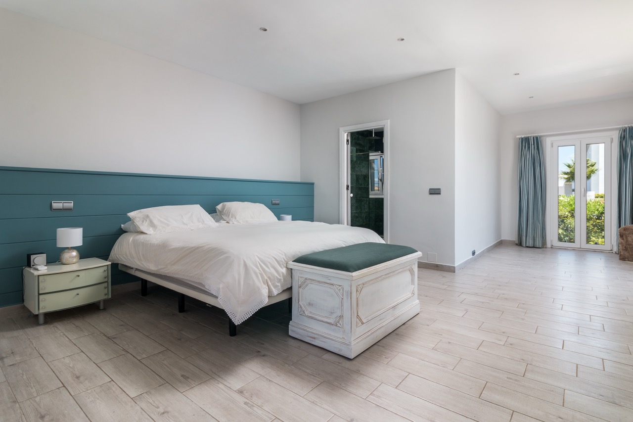 Dormitorio con cama doble, cabecero azul y acabados en blanco luminoso