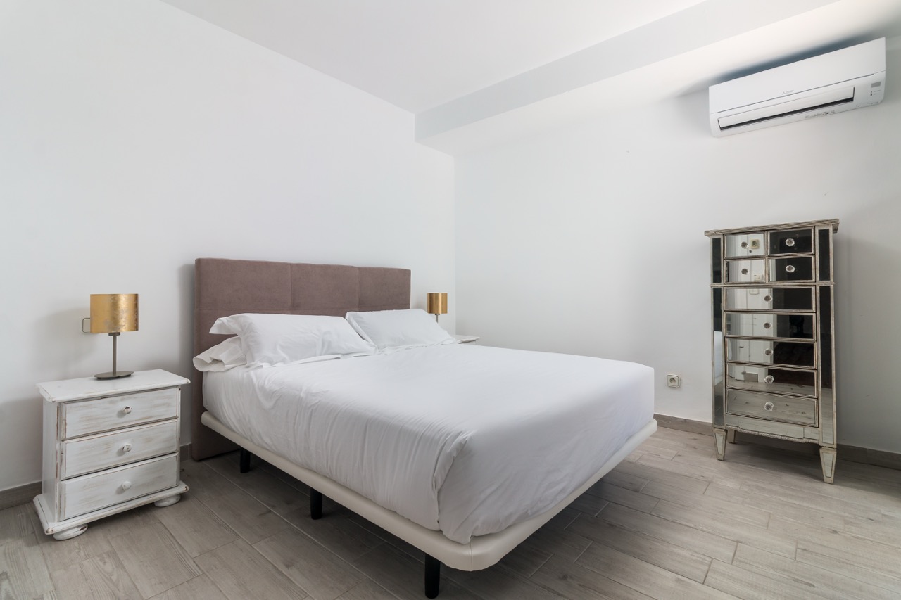 Dormitorio con cama doble, paredes blancas y cómoda