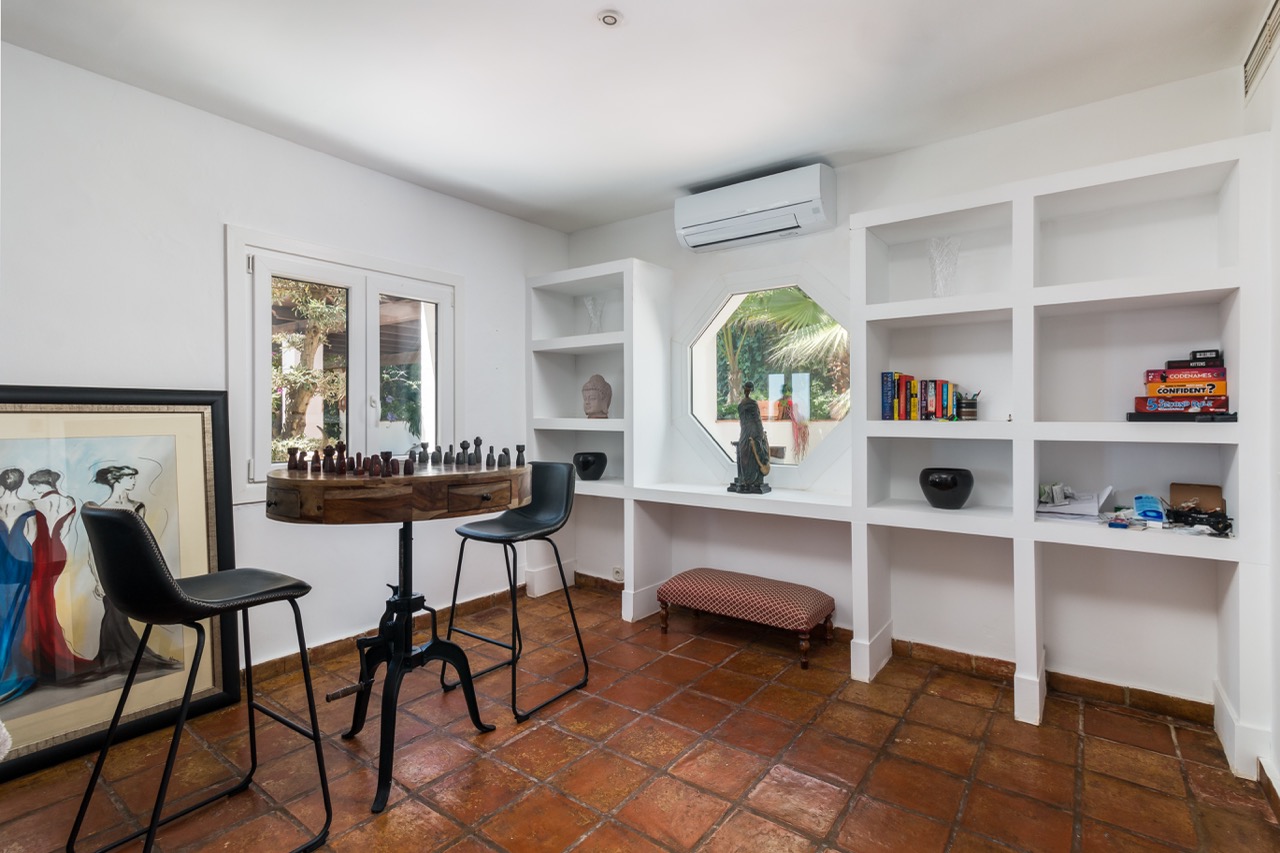 Despacho con escritorio, estanterías empotradas y ventana al jardín