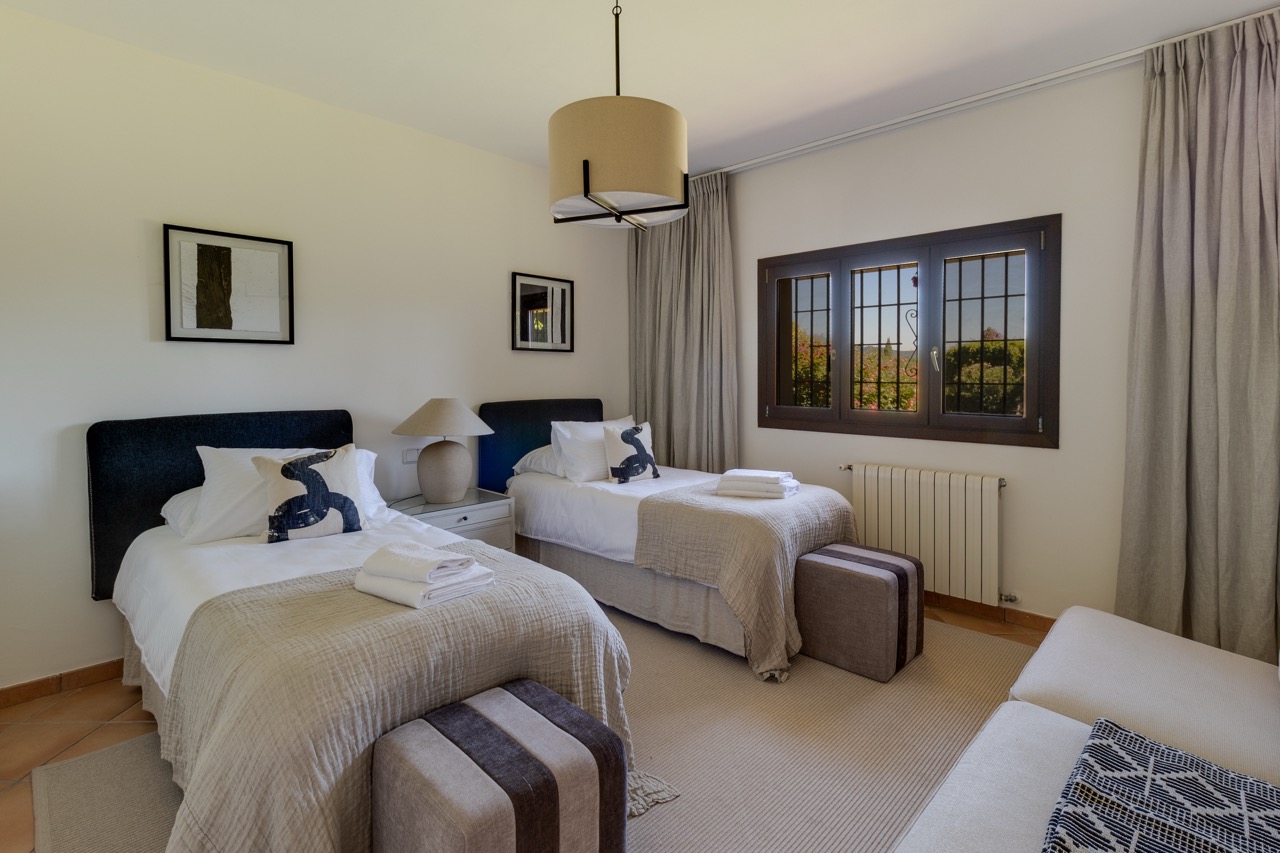 Dormitorio con dos camas individuales, suelo de madera y ventana