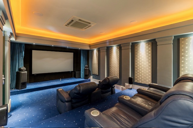 Sala de cine con pantalla grande, sofás e iluminación empotrada