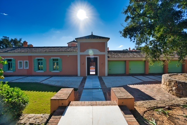 Frontline golf villa exterior with landscaped entrance and blue sky in Sotogrande Alto