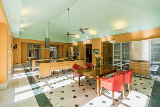 Kitchen and dining area with red chairs, checkerboard flooring and garden-facing windows