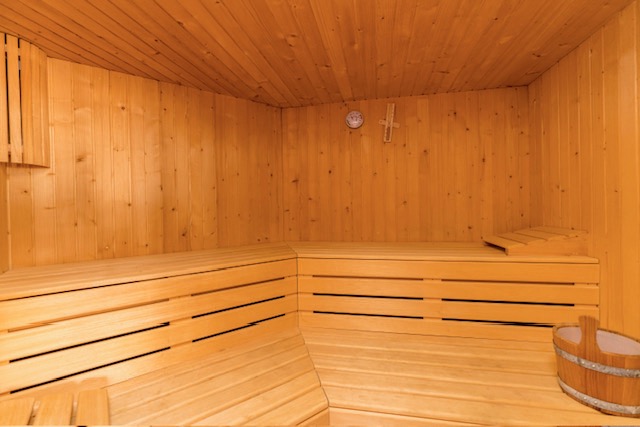 Wooden sauna with bench seating and warm lighting