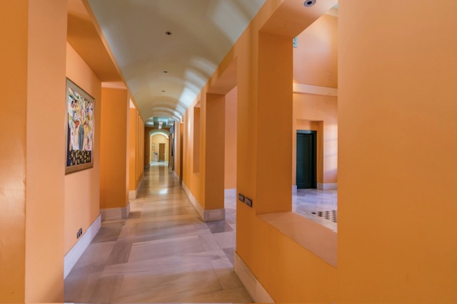 Hallway with orange walls, arched openings and tiled flooring