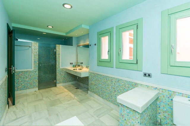 Bathroom with bathtub, vanity unit and green tiled walls