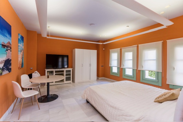 Bedroom with orange walls, white sofa and large windows