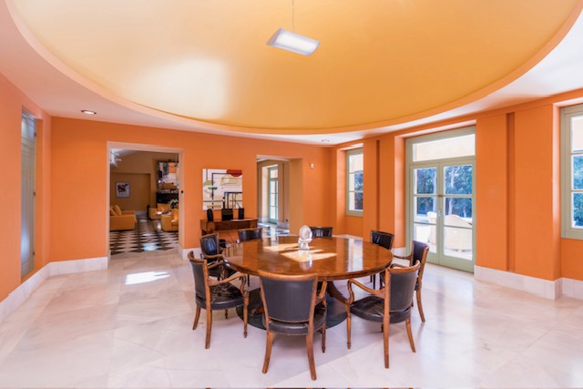 Dining room with round table, orange walls and large windows