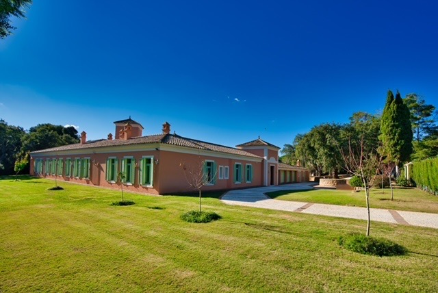 Frontline golf villa exterior with lawn, mature trees and terracotta façade