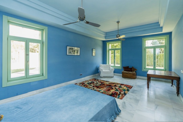 Blue bedroom or sitting room with sofa, tiled flooring and large windows