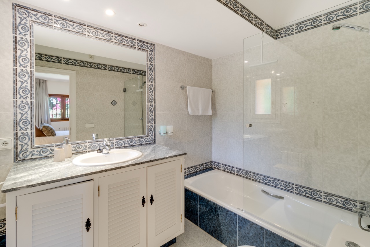 Baño con espejo enmarcado en mosaico y bañera