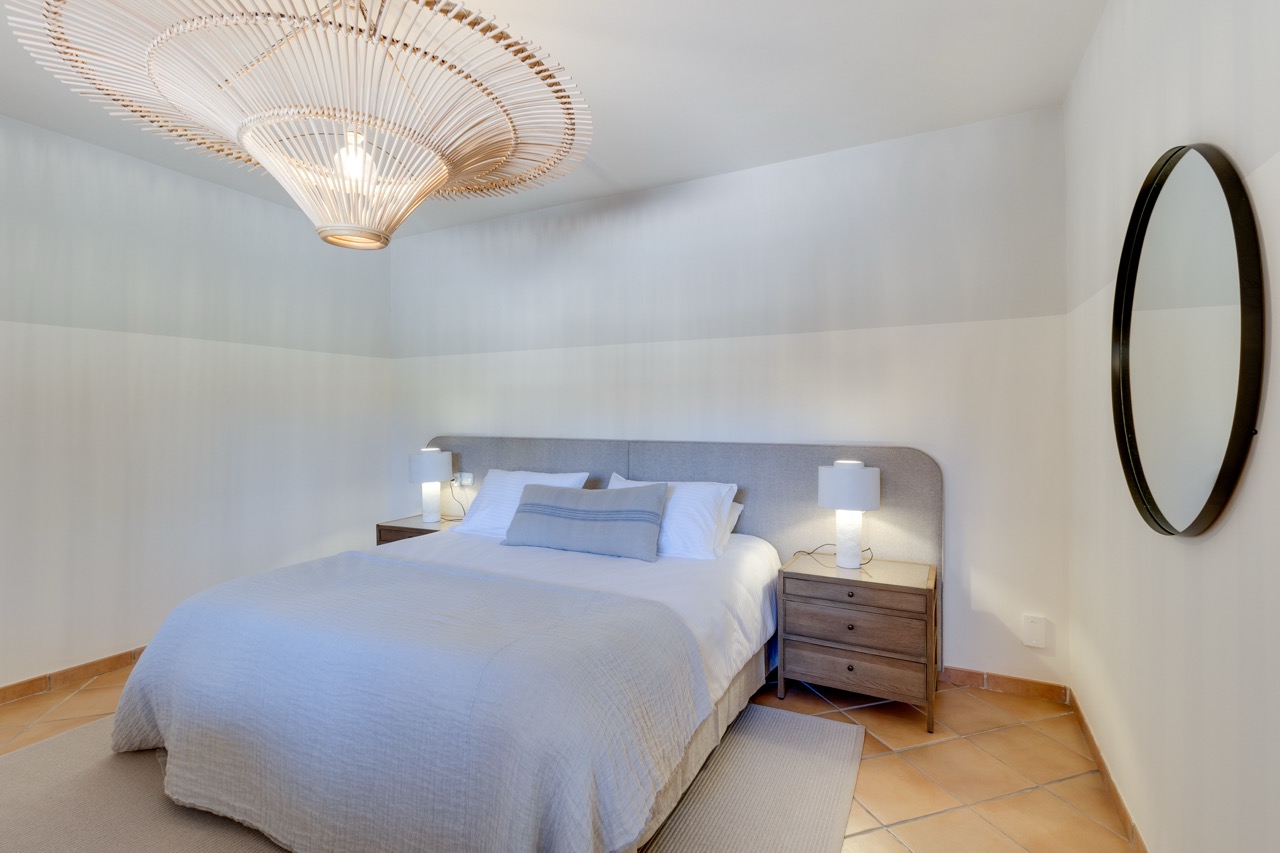 Dormitorio con cama doble, mesitas de noche y acabados en tonos neutros suaves
