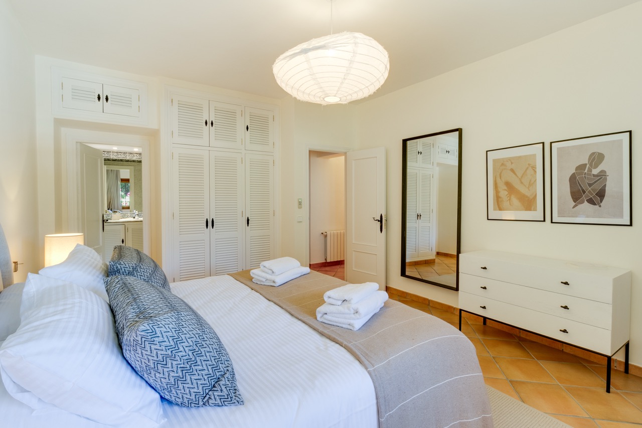 Dormitorio con cama doble, armarios blancos y cuadros enmarcados
