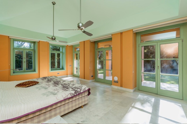 Bedroom with bed, yellow walls and large garden-facing doors