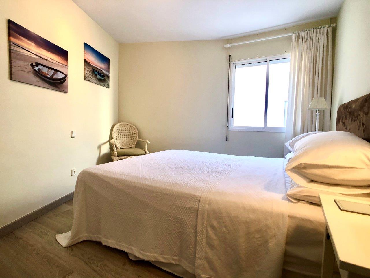 Dormitorio con cama doble, suelo de madera y luz natural