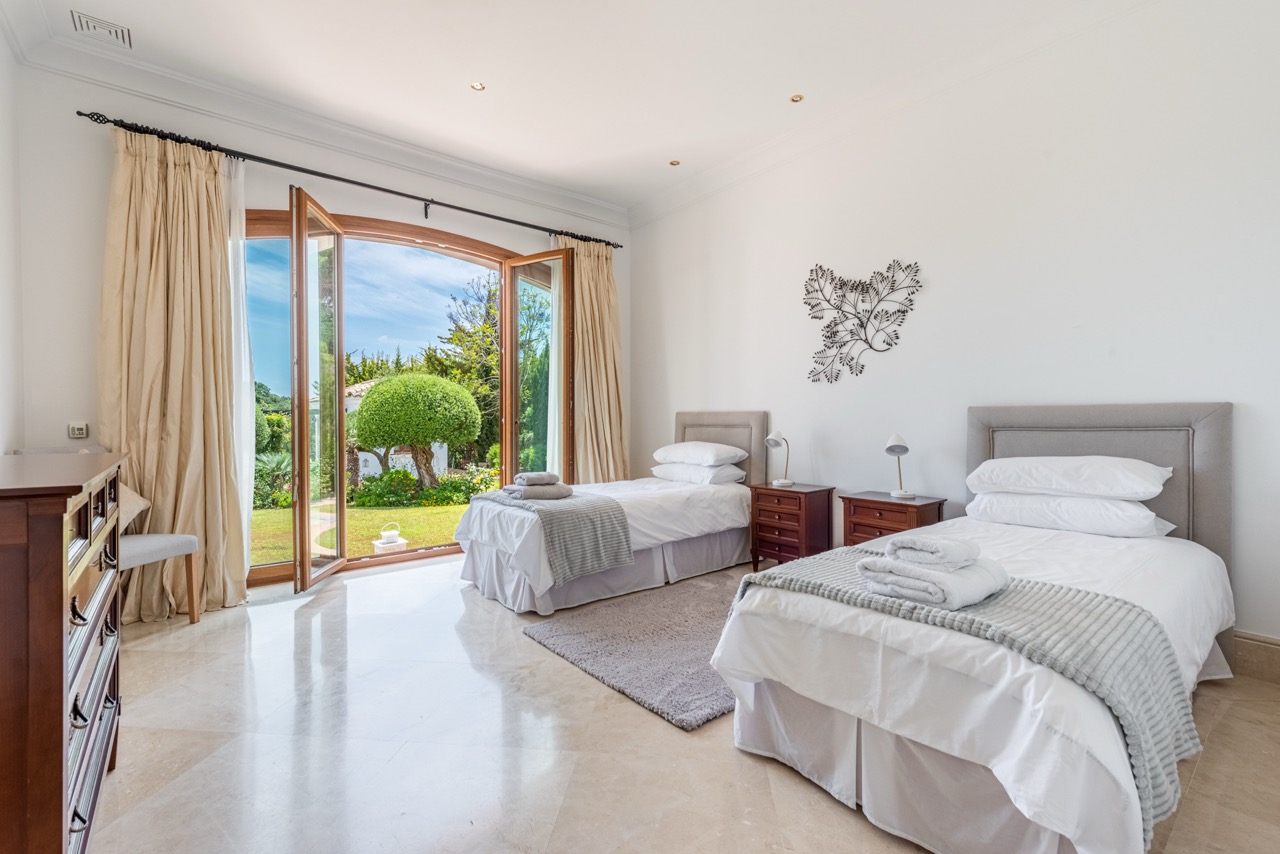Bedroom with twin beds, garden-facing window and neutral decor
