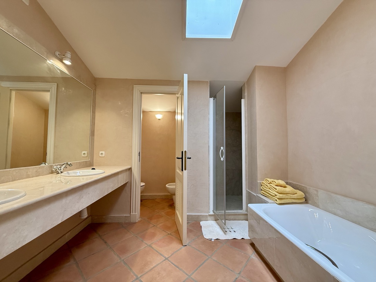 Bathroom with bathtub, long vanity and skylight